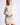 Model wearing Chiara white long-sleeve pullover sweater with white shorts