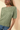 Close-up view of model wearing sage green ribbed knit top