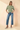 Full-length view of model wearing sage green ribbed knit top with blue jeans