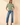 Full-length view of model wearing sage green ribbed knit top with blue jeans