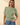 Front view of model wearing sage green ribbed knit top with blue jeans
