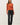 Full-length view of model wearing orange button-up cardigan with black pants