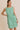 Model wearing a BOAT NECK SLEEVELESS SIDE TIES MINI DRESS in green and white stripes.