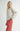 Side view of model wearing Irisha oatmeal diamond pointelle sweater with red pants