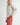 Side view of model wearing Irisha oatmeal diamond pointelle sweater with red pants