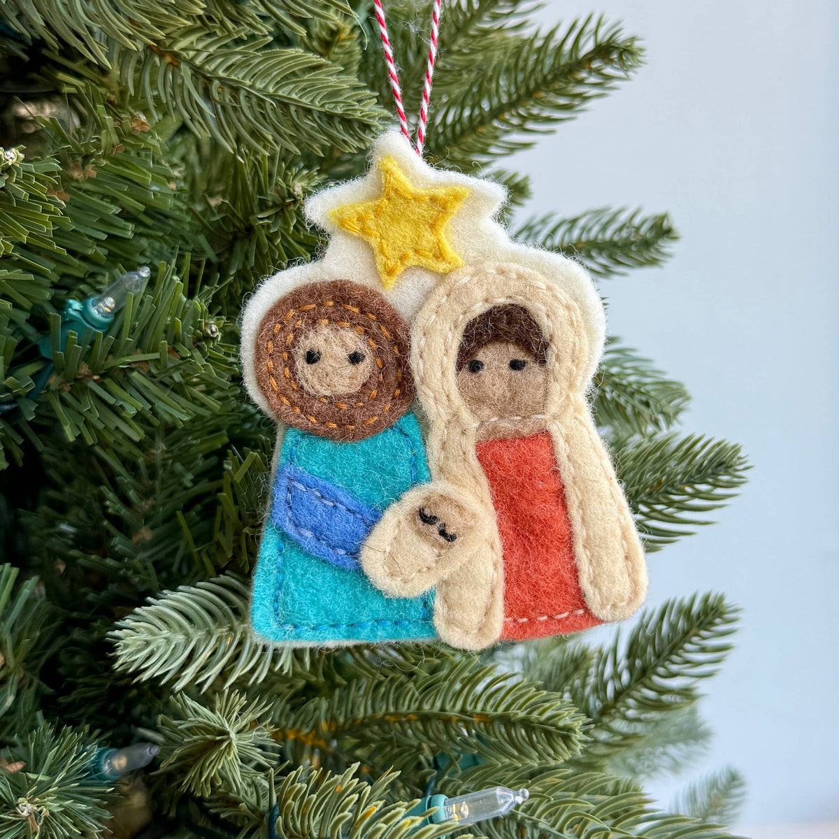 Nativity Felt Wool Christmas Ornament displayed outdoors on greenery
