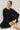 Model wearing black short sleeve top while sitting