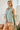 Model wearing a Striped Yoke Top in green, showcasing a casual summer look with light shorts.