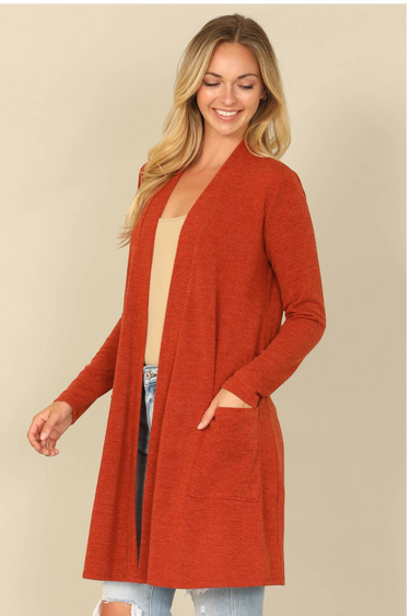 Shop Wall rust orange long sleeve open front cardigan with side pockets worn by a smiling blonde woman