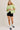 Full-length view of model wearing green short sleeve sweater cardigan with black shorts
