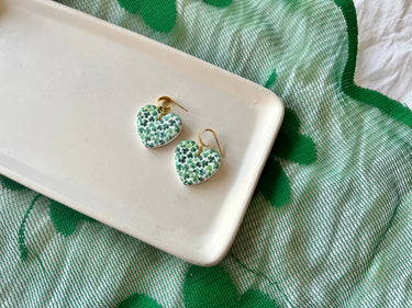 Shamrock Heart Earrings Clover Heart Earrings on a white platter with a green patterned cloth background.