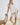 White collared V neck button down line lace detail shirt with beige shorts, seated pose