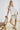 White collared V neck button down line lace detail shirt with beige shorts, seated pose