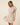 Shop Wall beige striped mini dress with notch neck, short sleeves, button-up detail, and smocked waist on a model.