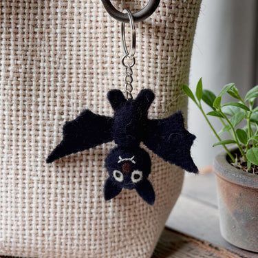 Bat Felt Wool Keychain hanging from a beige textured bag