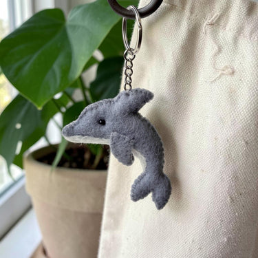 Dolphin Felt Wool Keychain hanging from a canvas tote bag