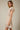 Shop Wall model wearing a beige and white striped notch neck short sleeve mini dress with a smocked waist
